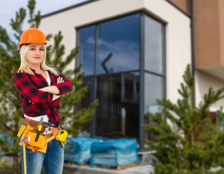 happy woman on the background of a new house. portrait of first time buyer, house owner, apartment renter, flat tenant or landlady. moving day and buying own property concept